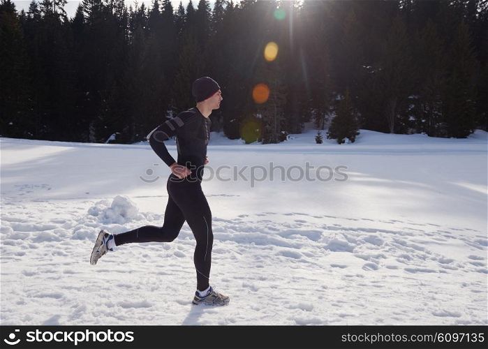young man jogging on snow in forest, bautiful sunny winter day. handsome sporty ahtlete man running