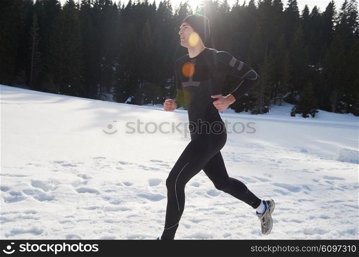 young man jogging on snow in forest, bautiful sunny winter day. handsome sporty ahtlete man running