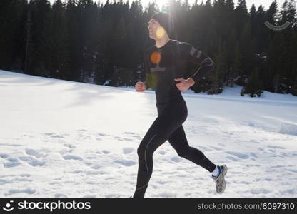 young man jogging on snow in forest, bautiful sunny winter day. handsome sporty ahtlete man running