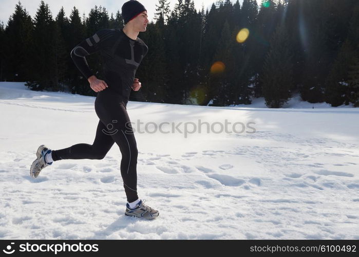 young man jogging on snow in forest, bautiful sunny winter day. handsome sporty ahtlete man running