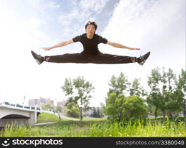 Young man jumping in the air near bridge under clear sky