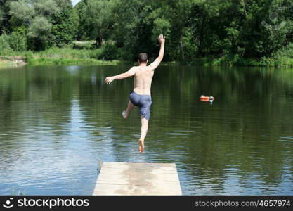 Young man jumping into lake