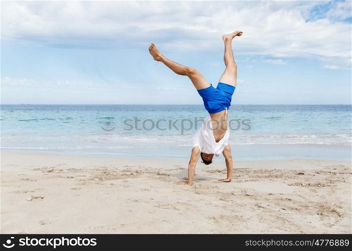 Young man jumping on beach. Young man having fun and jumping on beach