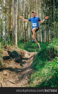 Young man jumping participating in a trail race through the forest. Man jumping participating in trail race