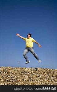 young man jumps on beach, with the sky as background