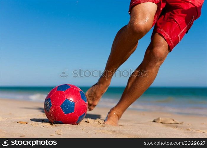 Young man (just feet) on the beach playing soccer in his vacation, he is about to kick the ball