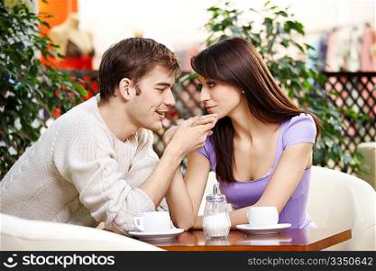 Young man kisses a hand to the beautiful girl on cafe