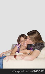 Young man kissing a young woman on a couch