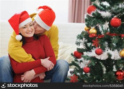 Young man kissing girlfriend near Christmas tree
