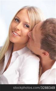 Young man kissing his girlfriend in a cheek