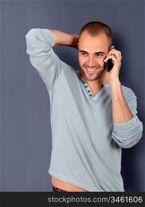 Young man leaning on blue wall with mobile phone