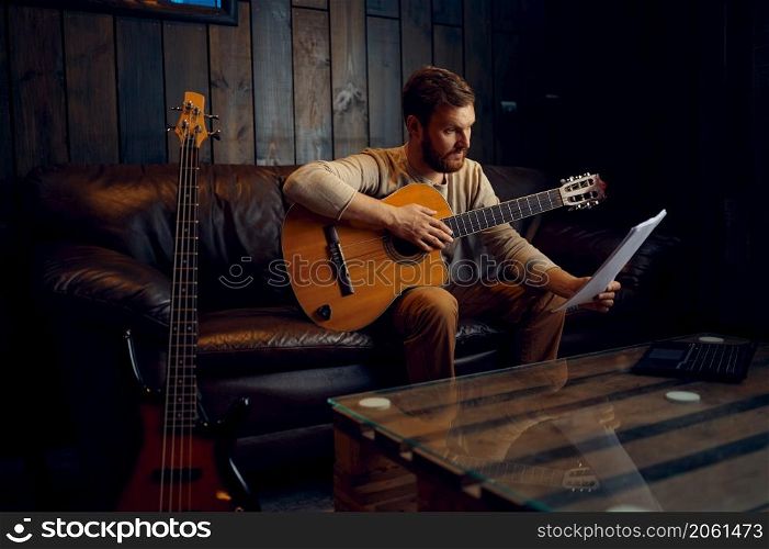 Young man learning play guitar at home reading musical notes. Online lesson, distance education. Young man learning play guitar at home