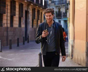 Young man listening music with smartphone earphones walking in the street