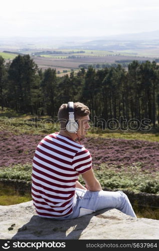 Young Man Listening To Music In Countryside On Headphones