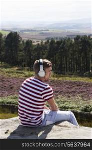 Young Man Listening To Music In Countryside On Headphones