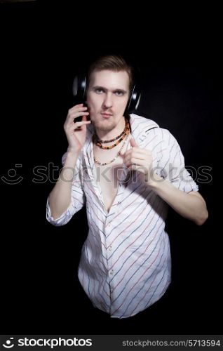 young man listening to music through headphones on black background