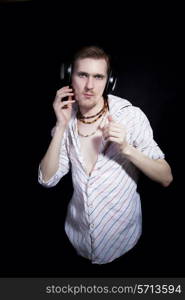 young man listening to music through headphones on black background