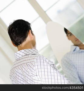 Young man looking at himself in a mirror