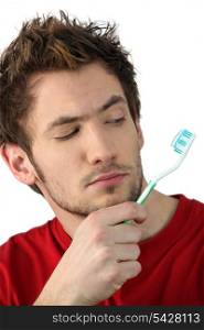Young man looking at his toothbrush