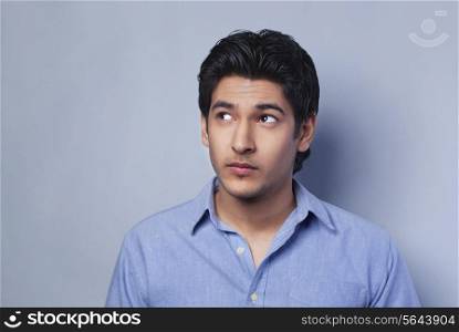 Young man looking away over colored background
