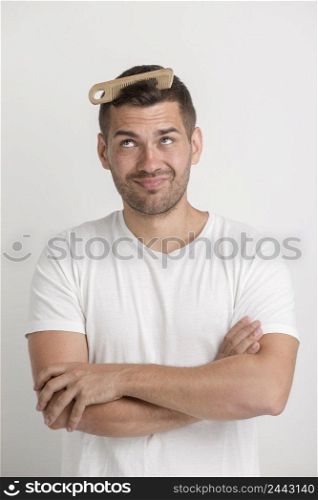 young man looking comb which is stuck his hair standing against white background