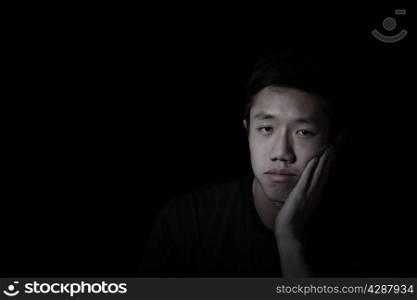 Young man, looking forward, showing depression with black background
