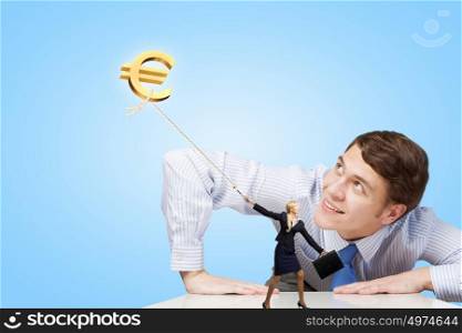 Young man looking from under table on euro symbol. How to make money