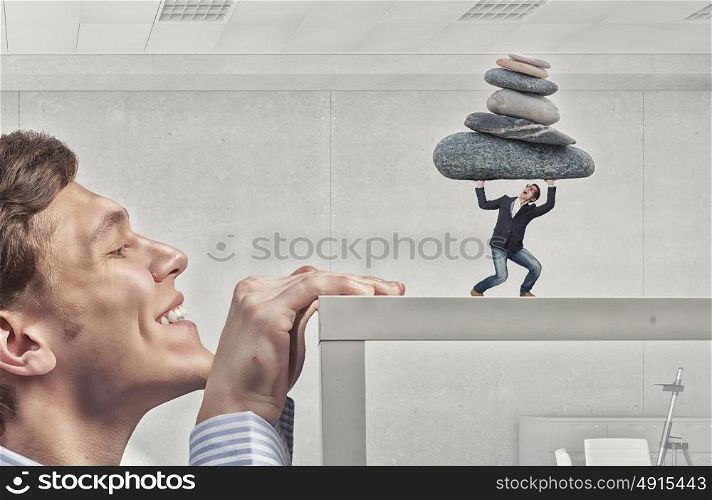 Young man looking from under table on guy lifting stones. Let others work