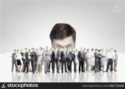 Young man looking from under table on large group of business people. They are professionals
