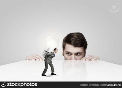 Young man looking from under table on man carrying bulb