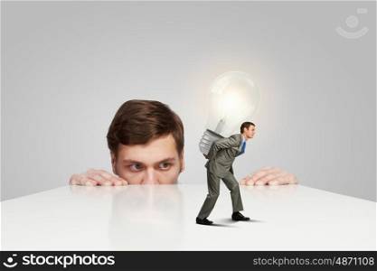 Young man looking from under table on man carrying bulb