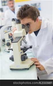 Young man looking in microscope