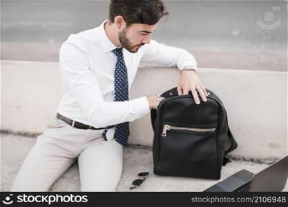 young man looking inside black backpack