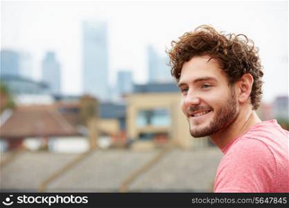 Young Man Looking Out Over City From Roof Terrace