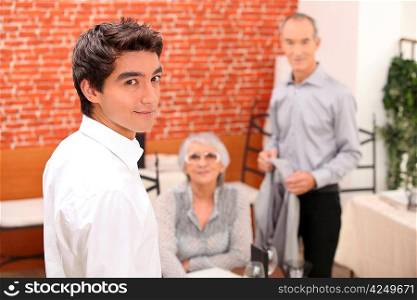 Young man looking over his shoulder as a senior couple make to leave a restaurant