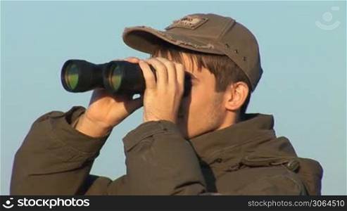 young man looking through binoculars
