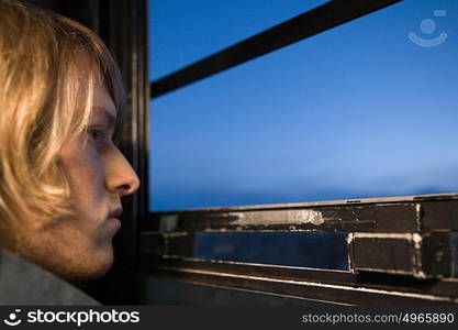 Young man looking through window