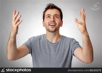 Young man looking up and worship God with raised hands