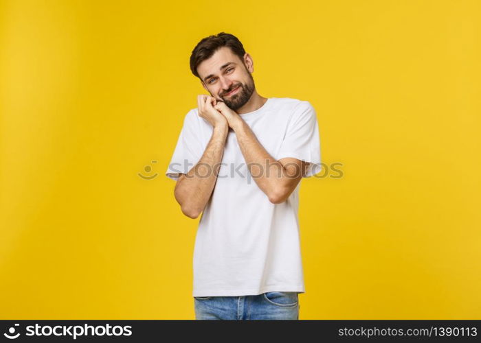 Young man looks to the camera and smiles shy. He&rsquo;s got his hands on cheek. Isolated, with a beard and a white T-shirt.. Young man looks to the camera and smiles shy. He&rsquo;s got his hands on cheek. Isolated, with a beard and a white T-shirt