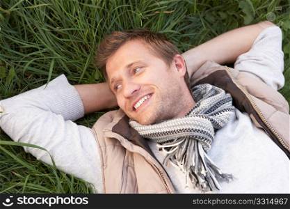Young man lying alone on grass