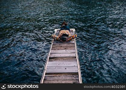 Young man lying down on pier at Shaver Lake, California, USA