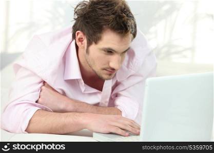 Young man lying in front of laptop