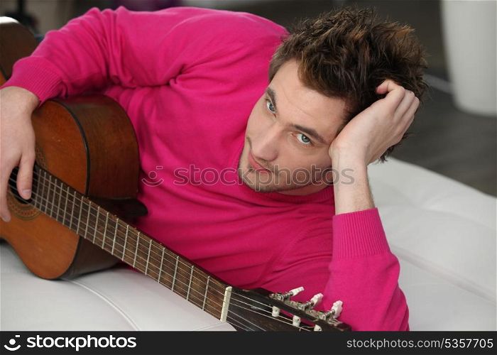 Young man lying on a couch with his guitar