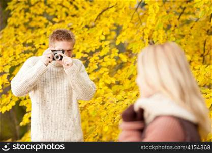 Young man make photo of posing woman profile in autumn park