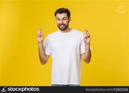 Young man making a wish isolated on yellow background.. Young man making a wish isolated on yellow background