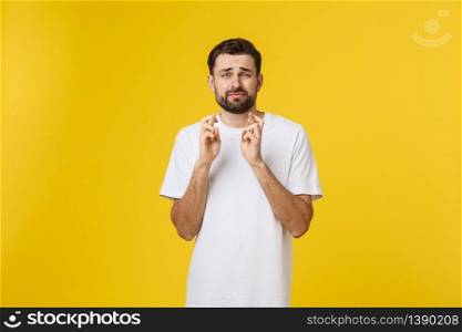 Young man making a wish isolated on yellow background.. Young man making a wish isolated on yellow background