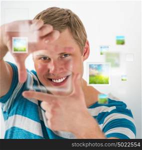 Young man making frame gesture with his fingers, virtual pictures are flying around. Uploading digital photo to social media concept