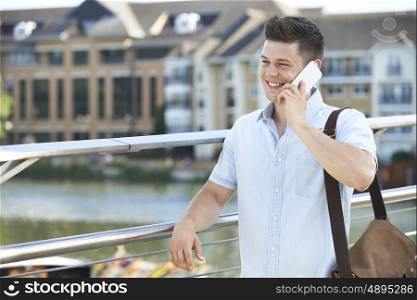 Young Man Making Phone Call On Mobile Phone Walking To Work