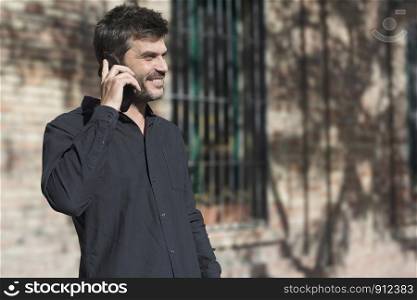 Young man making phone call walking on the street .
