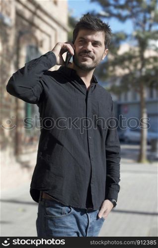 Young man making phone call walking on the street .